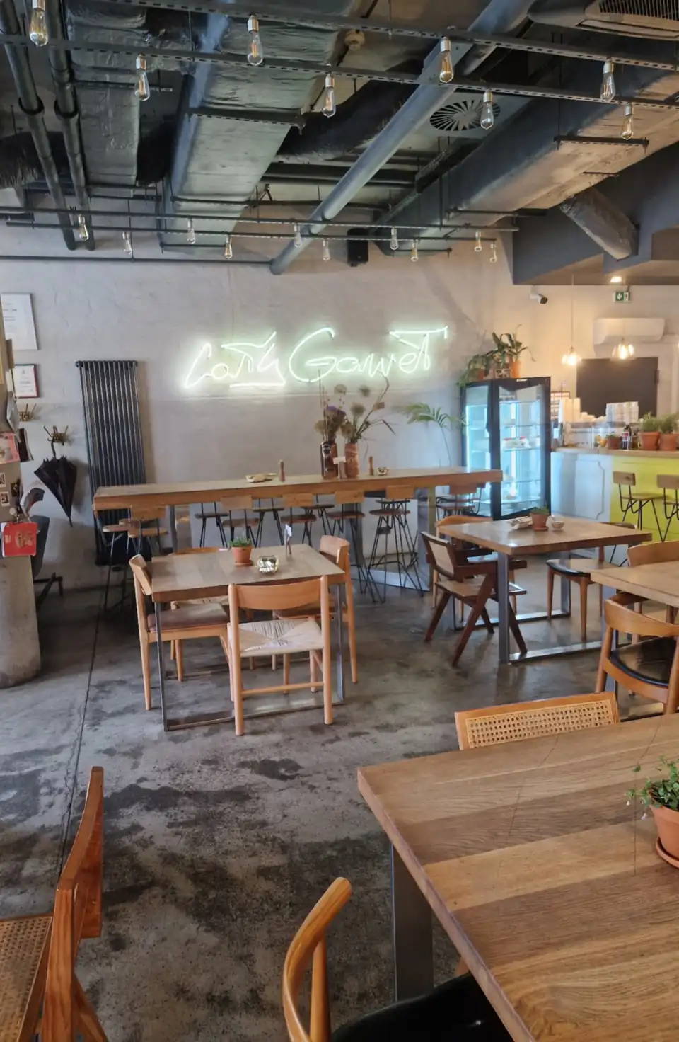 Cały Gaweł interior: concrete pillars, wooden tables, a yellow bar and the venue’s neon sign on the wall