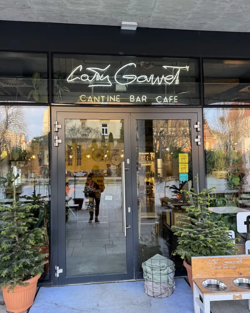 Entrance to Cały Gaweł with the Cantine Bar Cafe neon above the door and plants outside