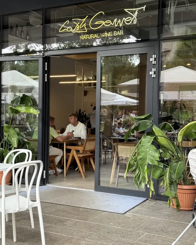 Shopfront with a Natural Wine Bar neon and white chairs outside